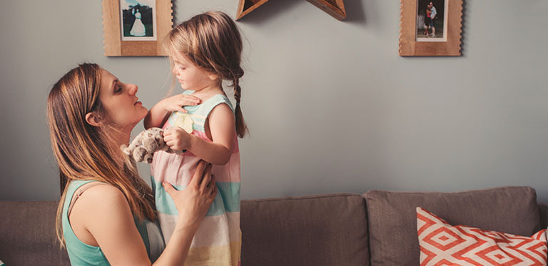mother and toddler daughter playing on the couch
